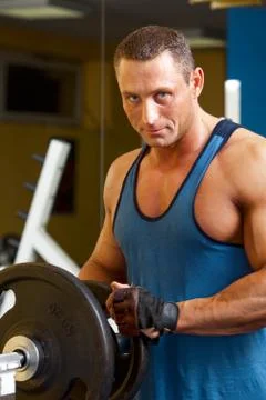 Strong man preparing his training machine in fitness Stock Photos