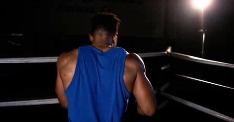 Strong man shadowboxes in an empty boxing ring at night Stock Footage 83380755