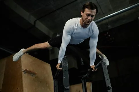 Strong Man in Static Hold on Parallel Bars Working out in Gym Stock-Fotos