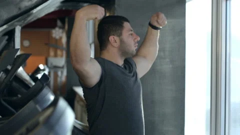 Strong man is stretching arms while standing in sports club indoors. Stock Footage 94195690