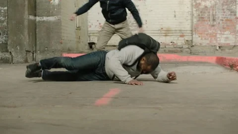 Strong man throws weaker man with an  wearing a black backpack on the ground, in Stock Footage 199458815