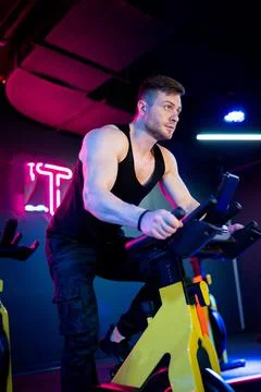Strong man training on bicycle indoor. Handsome young man cycling. Stock Photos