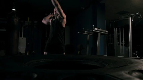 Strong man in training with a hammer and wheel Stock Footage 89604702