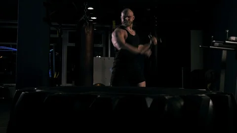 Strong man in training with a hammer and wheel Stock Footage 89604875