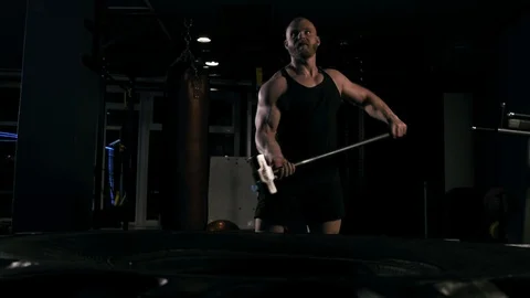 Strong man in training with a hammer and wheel Stock Footage 89605071