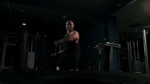 Strong man in training with a hammer and wheel Stock Footage 89605301