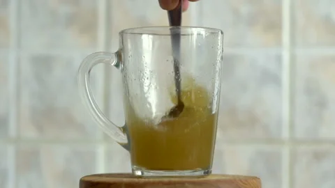 Strong mixing of the green herbal solution in a glass mug in slow motion Stock Footage 112722013