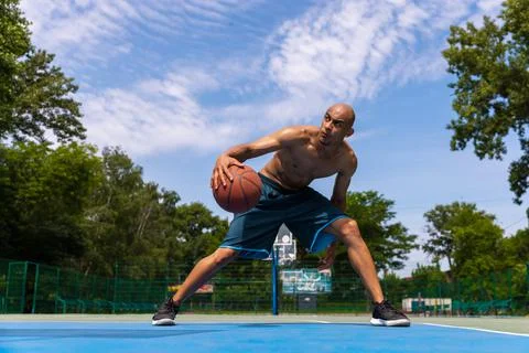 Strong muscular african-american male basketball player training at street Stock Photos