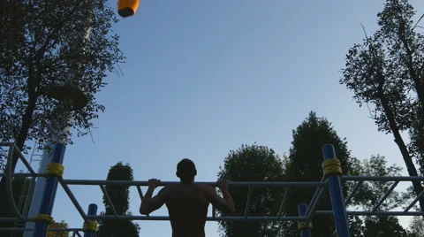 Strong muscular man doing pull ups in a park. Silhouette of fitness muscular man Vídeos de archivo 68529710