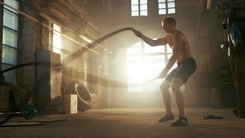 Strong Muscular Shirtless Sportsman Works out Hard with Battle Ropes Stock Footage