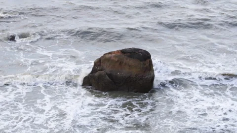 Strong ocean waves crashing over a rock in sea with white foam Video stock 340185687