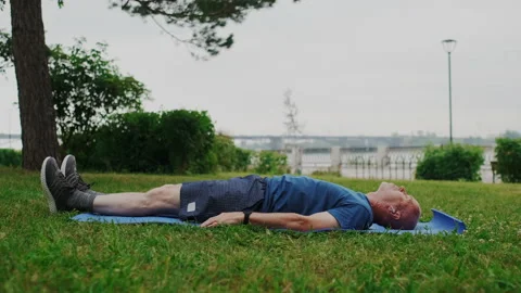 Strong Old Man Lying on Blue Sport Mat and Makes Fitness or Gymnastic Exercises Stock Footage 148316871