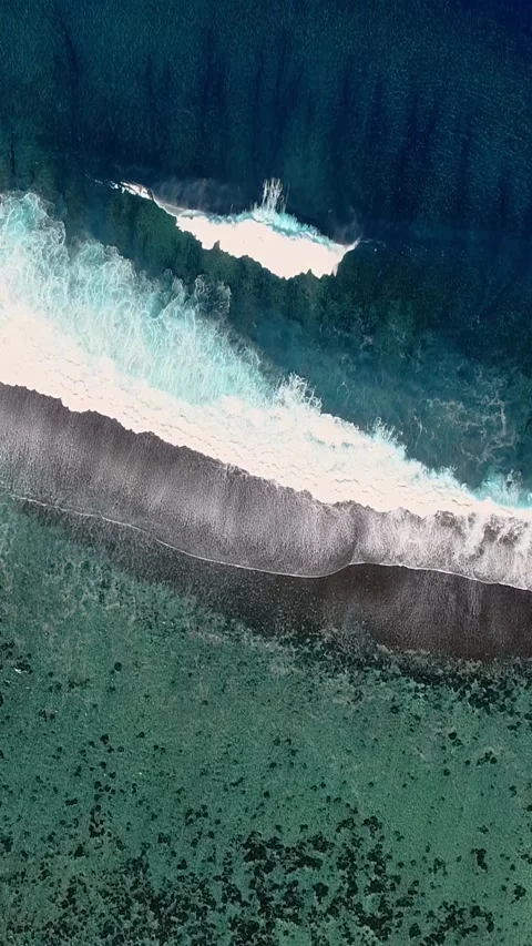 Strong Pacific waves splashing on black sand beach on overhead vertical video. Video stock 277933473