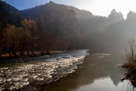 Strong river current with lots of rocks and shrubs in winter Stock Photos