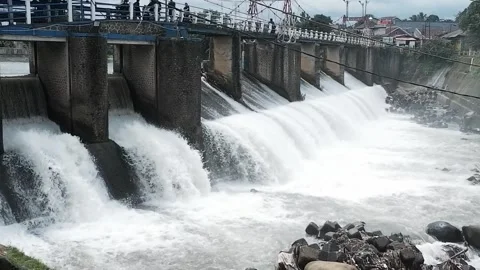 Strong river currents rush over a low katulampa concrete dam Stock Footage 328465587