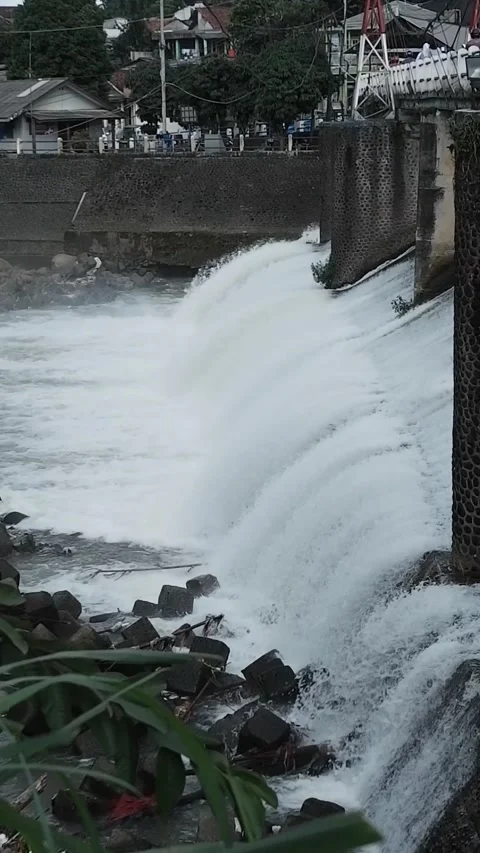 Strong river currents rush over a low katulampa concrete dam Stock Footage 328465642