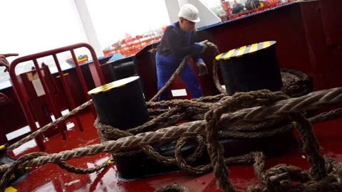Strong sailor winds thick rope around steel holders Stock Footage 318953680