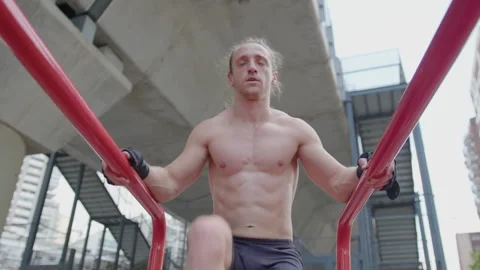 Strong Shirtless Man Doing Knee Raises on Parallel Bars Outdoor Stock Footage 260056494