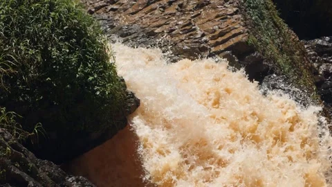 A strong splash of water flowing from between huge rocks in the mountain. Stock Footage 142695204