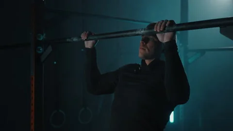 Strong sporty man doing workout and pulls up on horizontal bar in fitness gym Stock Footage 194044897