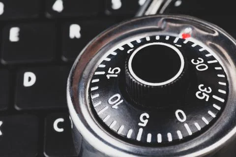 Strong steel coded lock, padlock laying on a black laptop keyboard, closeup Stock Photos