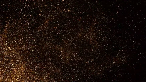 A strong stream of air blows a mass of gold particles from the left side of the Stock Footage 164571221