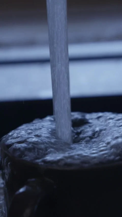 Strong stream of water flowing from kitchen faucet onto dishes in black sink. Cl Stock Footage 329542048
