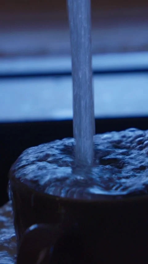 Strong stream of water flowing from kitchen faucet onto dishes in black sink. Cl Stock Footage 329542049