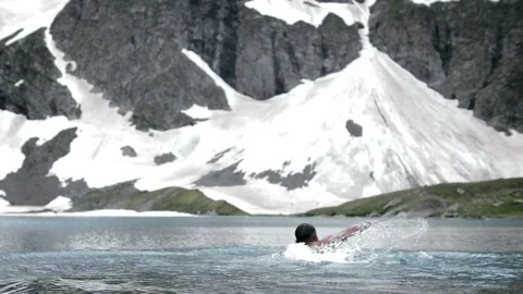 Strong tempered man with beard swim through the icy mountain lake Stock Footage 138689872