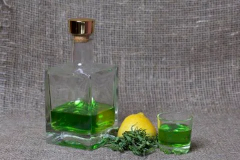 Strong tincture on tarhuna in a transparent rectangular bottle. Drink bright  库存照片