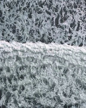 Strong waves crashing into the sand surface forming various textures Stock Photos