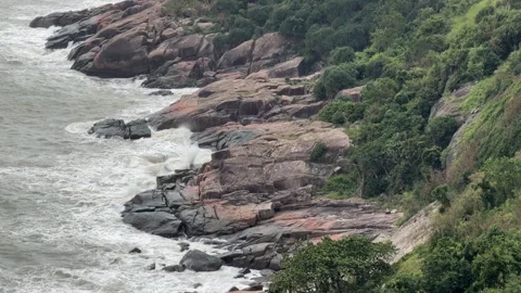 Strong waves roll against dark stone formations sending bright foam upward while Stock Footage 322574629