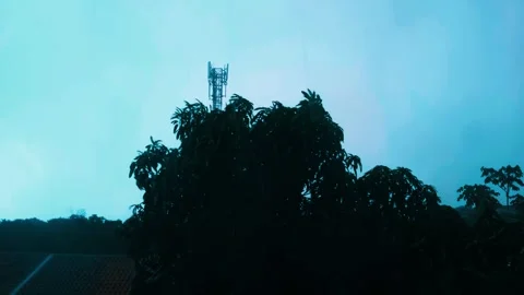 Strong wind and rain blowing trees, communication tower in background Stock-Footage 337404024