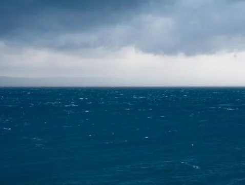 Strong wind and rainy clouds over blue sea Stock Photos