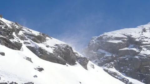 Strong wind blowing snow off mountain ridge on sunny day Stock Footage 317190477