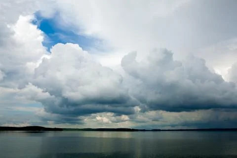 Strong wind drives clouds across the sky above the sea Stock Photos