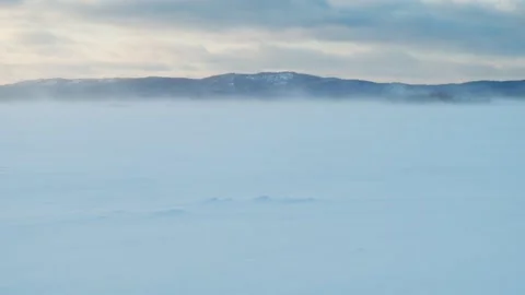 A strong wind is driving snow across the frozen lake's snow cover. Winter. Stock Footage 299798035