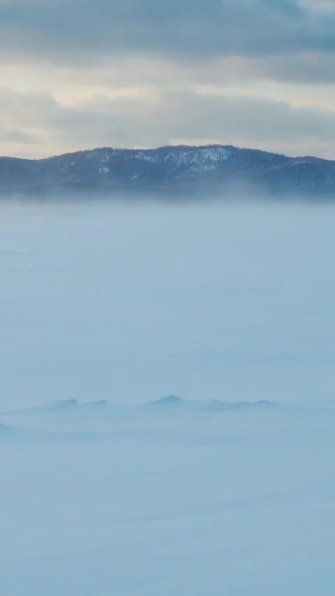 A strong wind is driving snow across the frozen lake's snow cover. Winter. Stock Footage 299975459