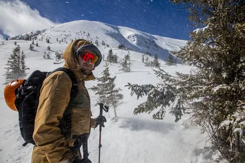 A strong wind sweeps the snow in front of the face of a hiker wearing mount.. Stock Photos