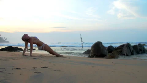 Strong woman does reverse plank pose on warm sand by ocean Stock Footage 270161092