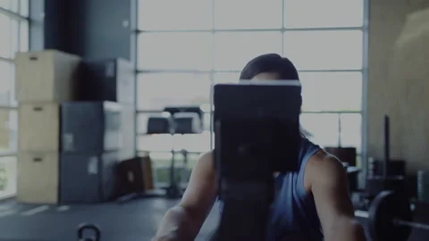 Strong woman exercises on rowing machine in gym, focused and determined Stock Footage 312704300