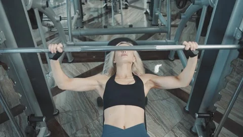 Strong woman performs bench press at gym training session for improved strength Video stock 313326694