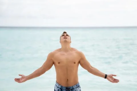 Strong young guy with a bare-chested looks to heaven. In the background is th Stock Photos