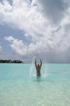 Strong young guy creates a spray of water when he jumps out of the water Foto stock