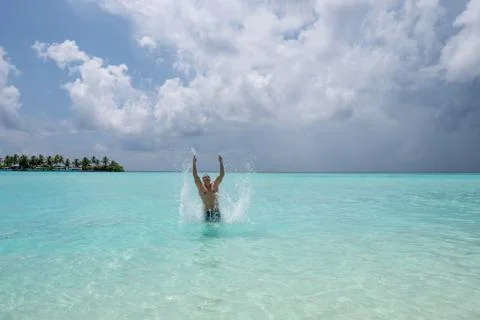 Strong young guy creates a spray of water when he jumps out of the water Foto stock