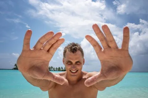 A strong young guy smiling pulls his hands to the camera. Stock Photos