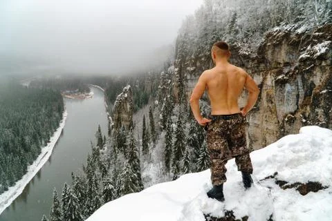 Strong young man with bare torso on mountain top covered with snow Stock Photos