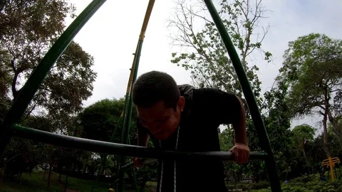 Strong young man is doing triceps dips on parallel bars. Exercising outdoors in Stock Footage 120025015