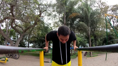 Strong young man is doing triceps dips on parallel bars. Exercising outdoors in 動画素材 120025279