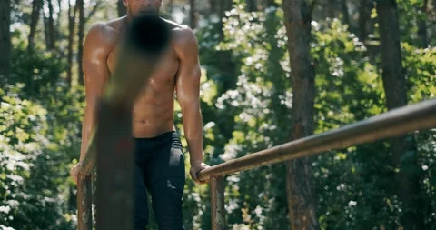 Strong young man is doing triceps dips on parallel bars. Exercising outdoors in 動画素材 121597944